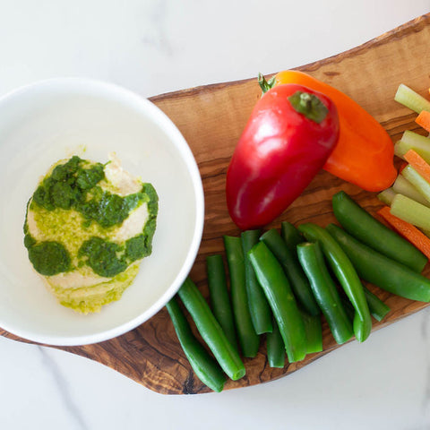 Assorted vegetables on a wooden cutting board with a bowl of dip.